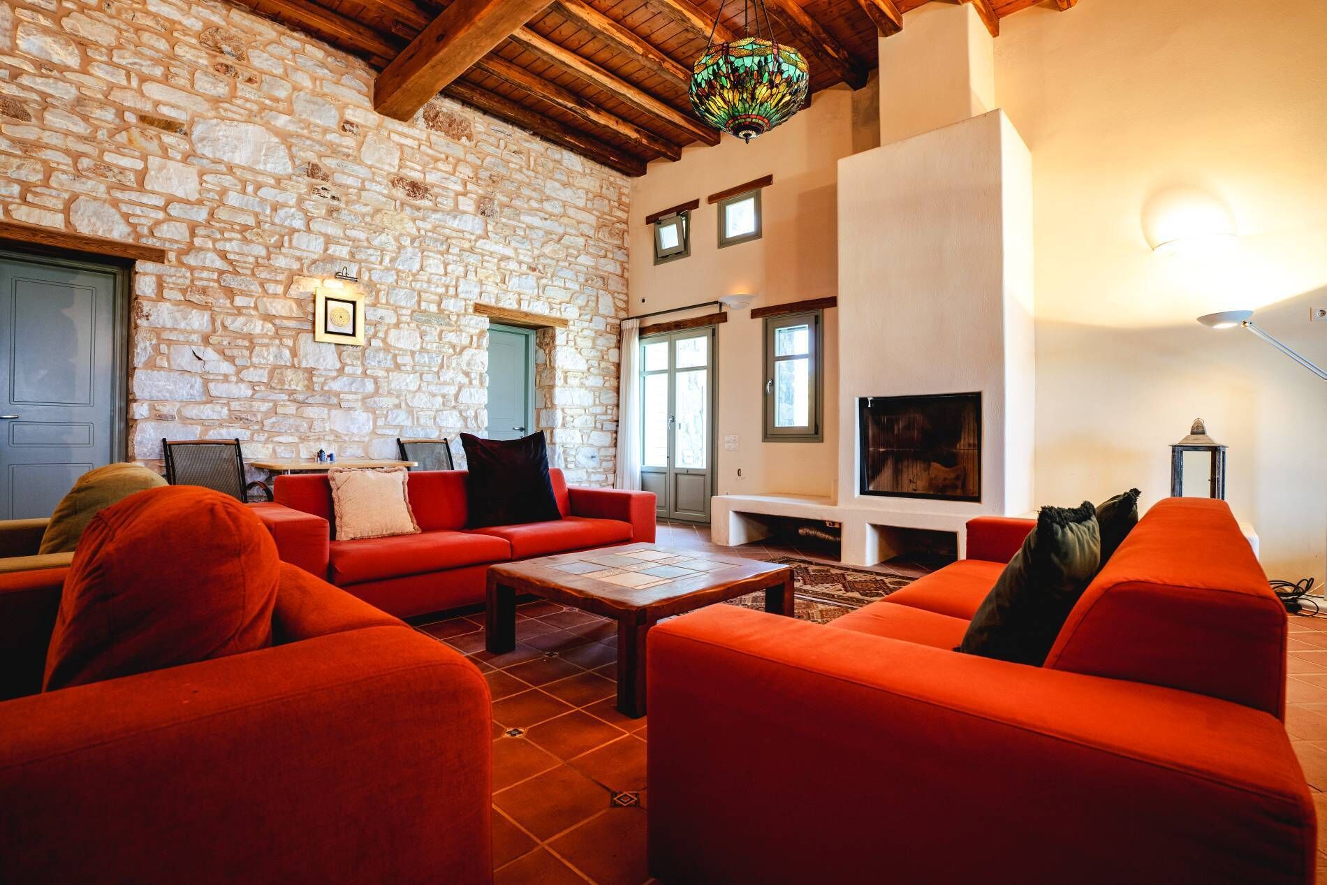 A cozy living room with stone walls, a fireplace, and red furniture.