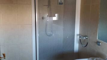 A bathroom with a glass-enclosed shower, a white sink, and tiled walls.