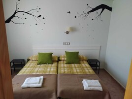 Habitación de hotel con cama, dos almohadas, dos mesitas de noche y un adorno en la pared.