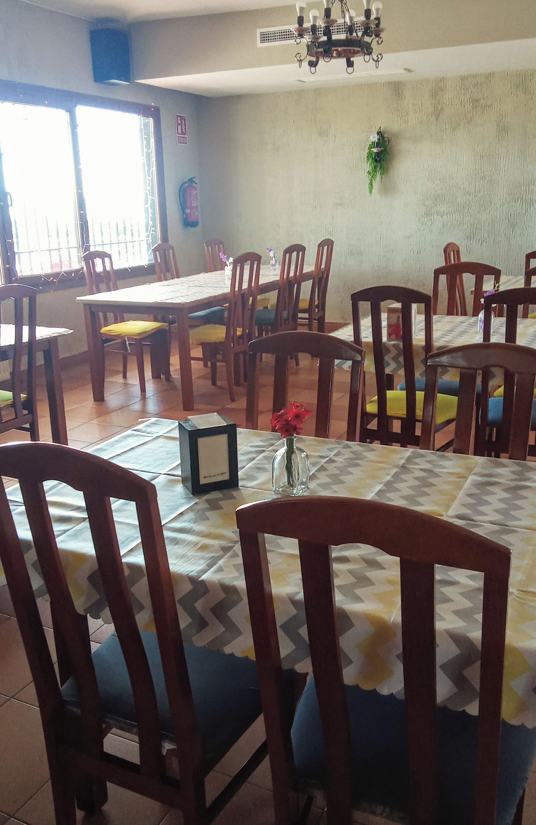 A dining area with multiple tables and chairs, a chandelier, and a potted plant on the wall.