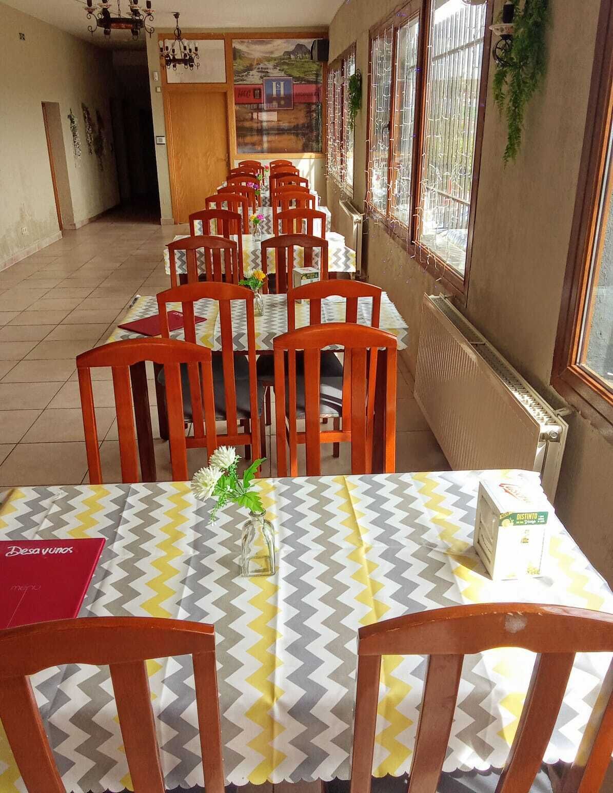 Un coin repas avec des chaises et des tables en bois, une vue sur la rue et un radiateur fixé au mur.