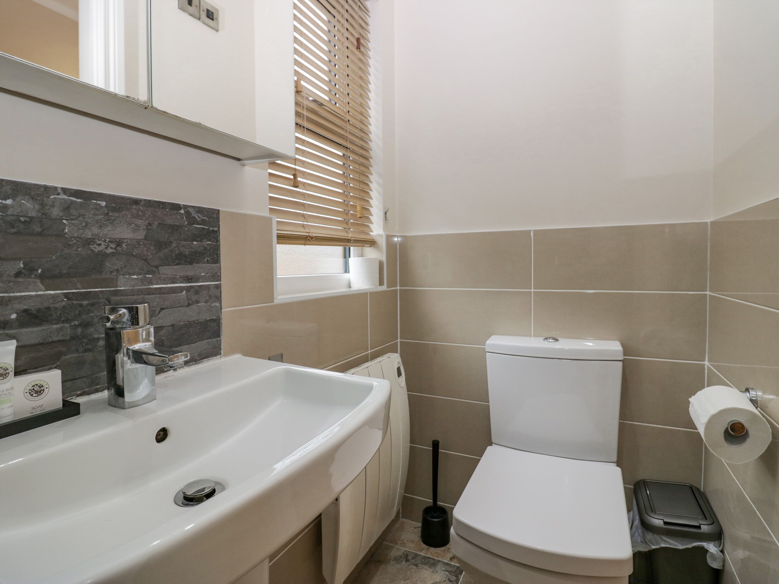 Un baño con un lavamanos blanco, un inodoro y un cubo de basura.