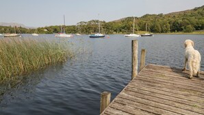 A wooden dock extending into calm water with boats and greenery in the background. - 8 Woodlands (Ulverston)