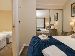 A hotel room with a large bed, a smaller bed, a wardrobe, a nightstand, and a lamp. - 8 Woodlands (Ulverston)