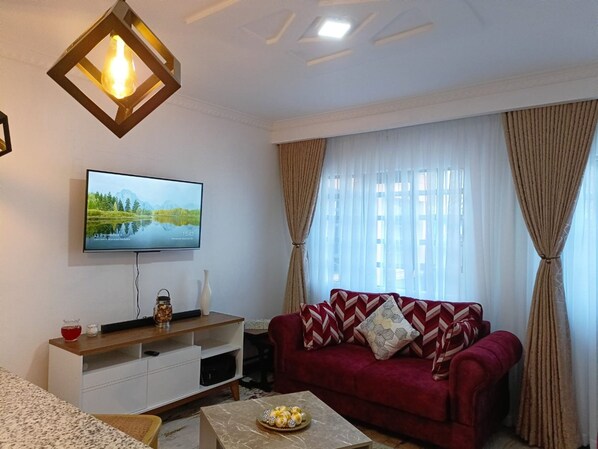 Departamento Deluxe, 1 habitación | Área de sala de estar | Televisión de pantalla plana de 24 pulgadas con canales digitales 