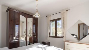 A bedroom with a bed, a dresser, a mirror, and a window with curtains. - Apartment Aurora by Interhome (Costarainera)