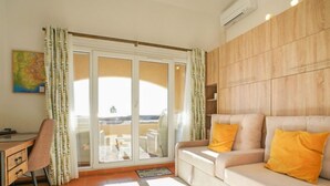 A room with a sofa, a desk, and a view through a glass door. - Roche Rouge by Interhome (Théoule sur mer)