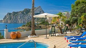 Zona de piscina amb gandules, una piscina i vista al mar i a les muntanyes.