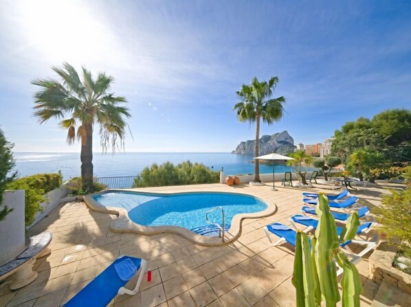 A pool area with a view of the sea, palm trees, and lounge chairs. - Flora Mar by Interhome (Calpe/Calp)