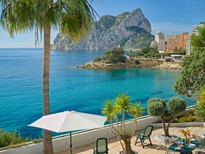 A coastal view with a clear blue sea, a rocky outcrop, and a building in the background. - Flora Mar by Interhome (Calpe/Calp)