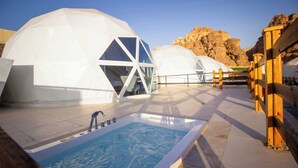 A series of white geodesic domes with a pool and wooden deck in the foreground. - The Rock Camp Petra (Wadi Musa)
