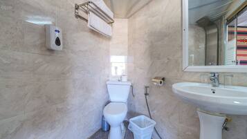 A small, modern bathroom with a toilet, sink, and hand dryer.