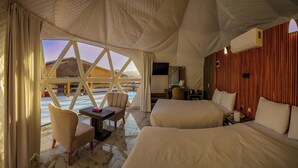 A spacious tented room with two beds, a small table, and a chair. - The Rock Camp Petra (Wadi Musa)