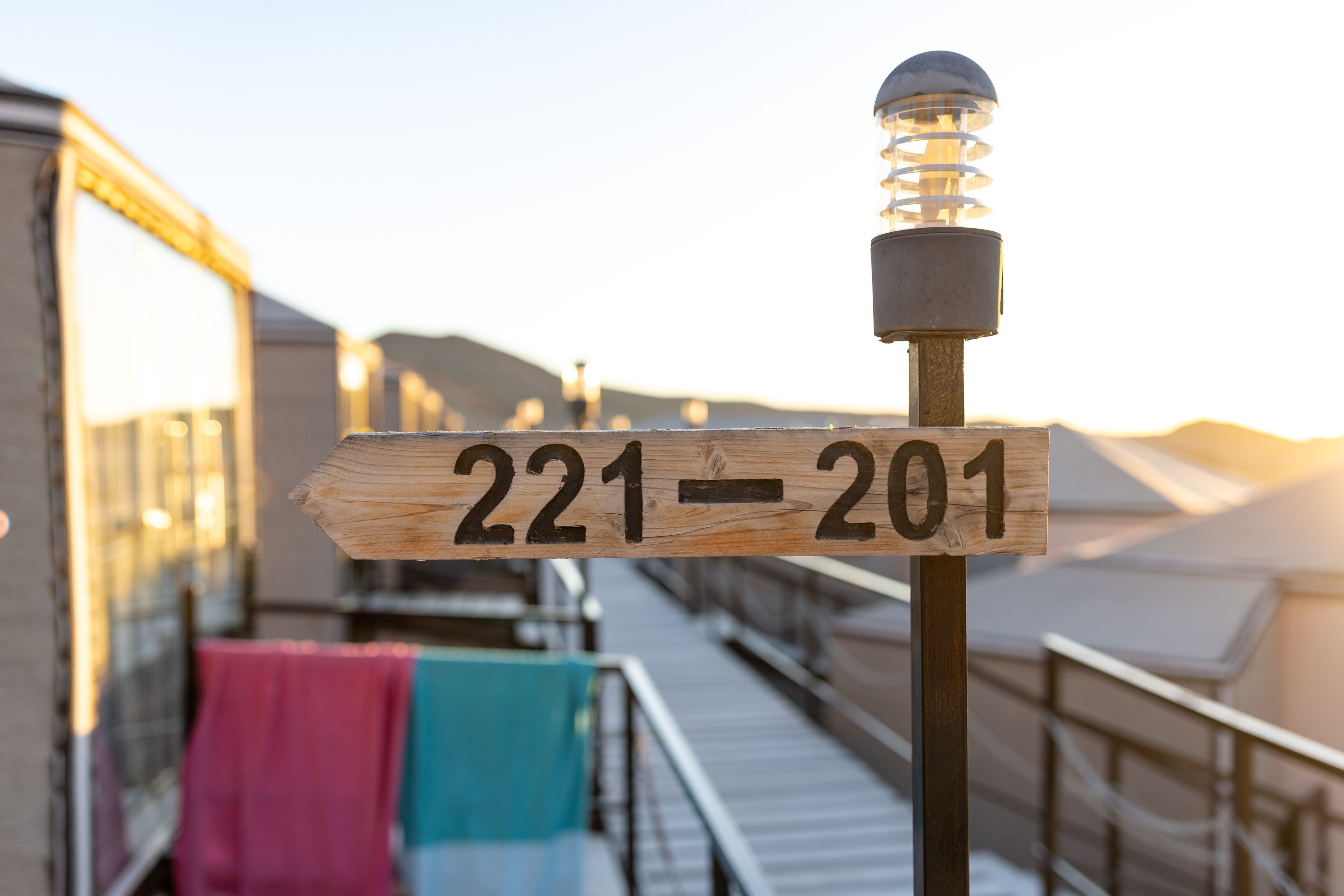 A wooden sign with the numbers "221-201" on a balcony railing.