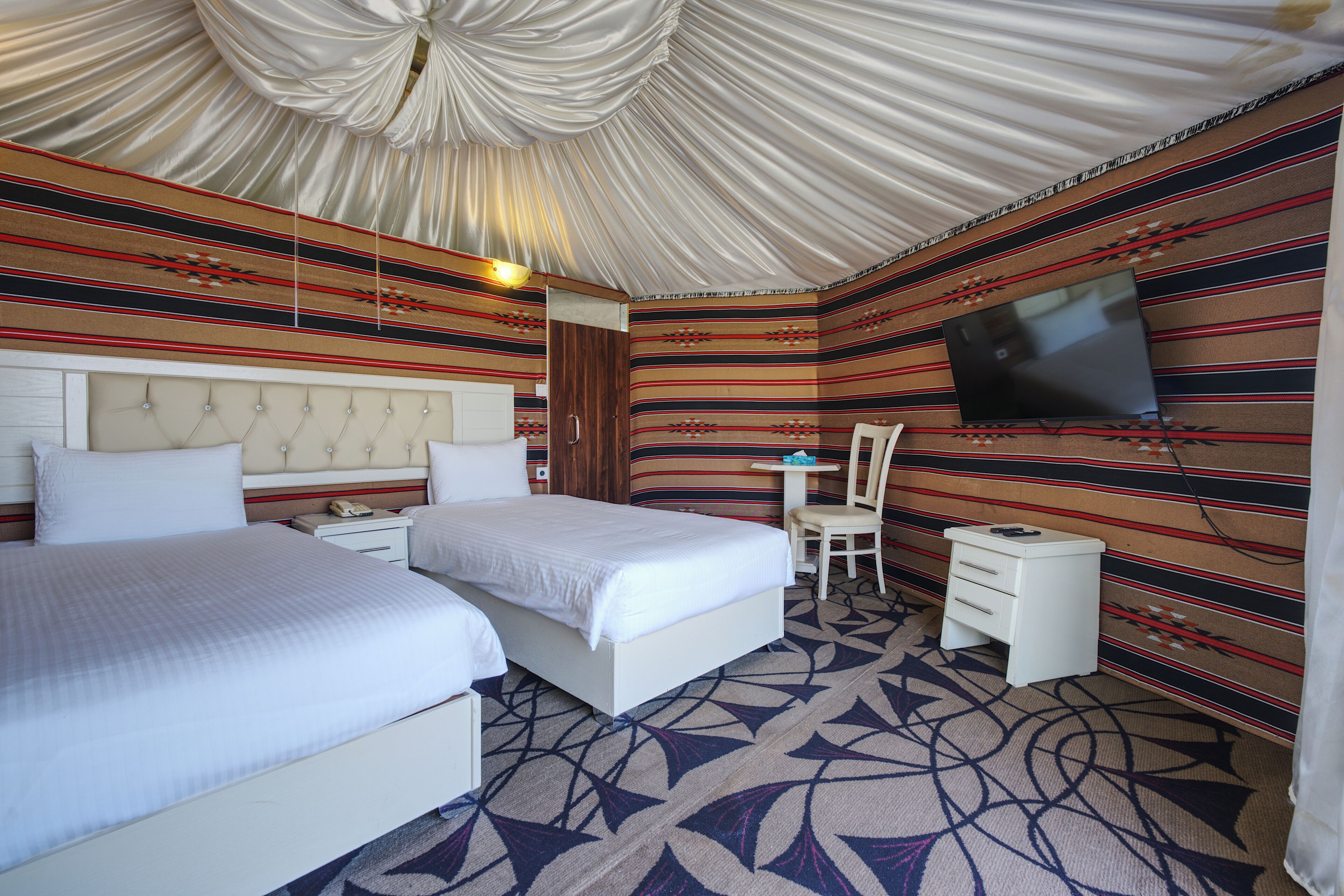 A room with two beds, a TV, a desk, and a chair.