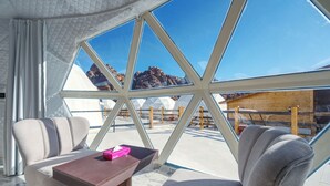 A modern room with a large glass window, a wooden table, and two sofas. - The Rock Camp Petra (Wadi Musa)