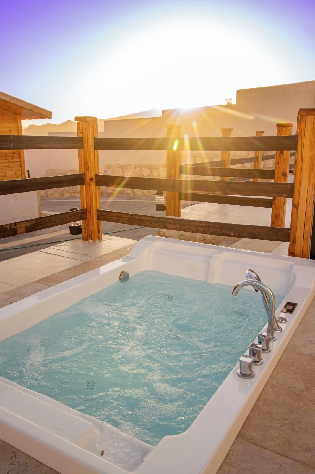 A hot tub with a wooden fence in the background.