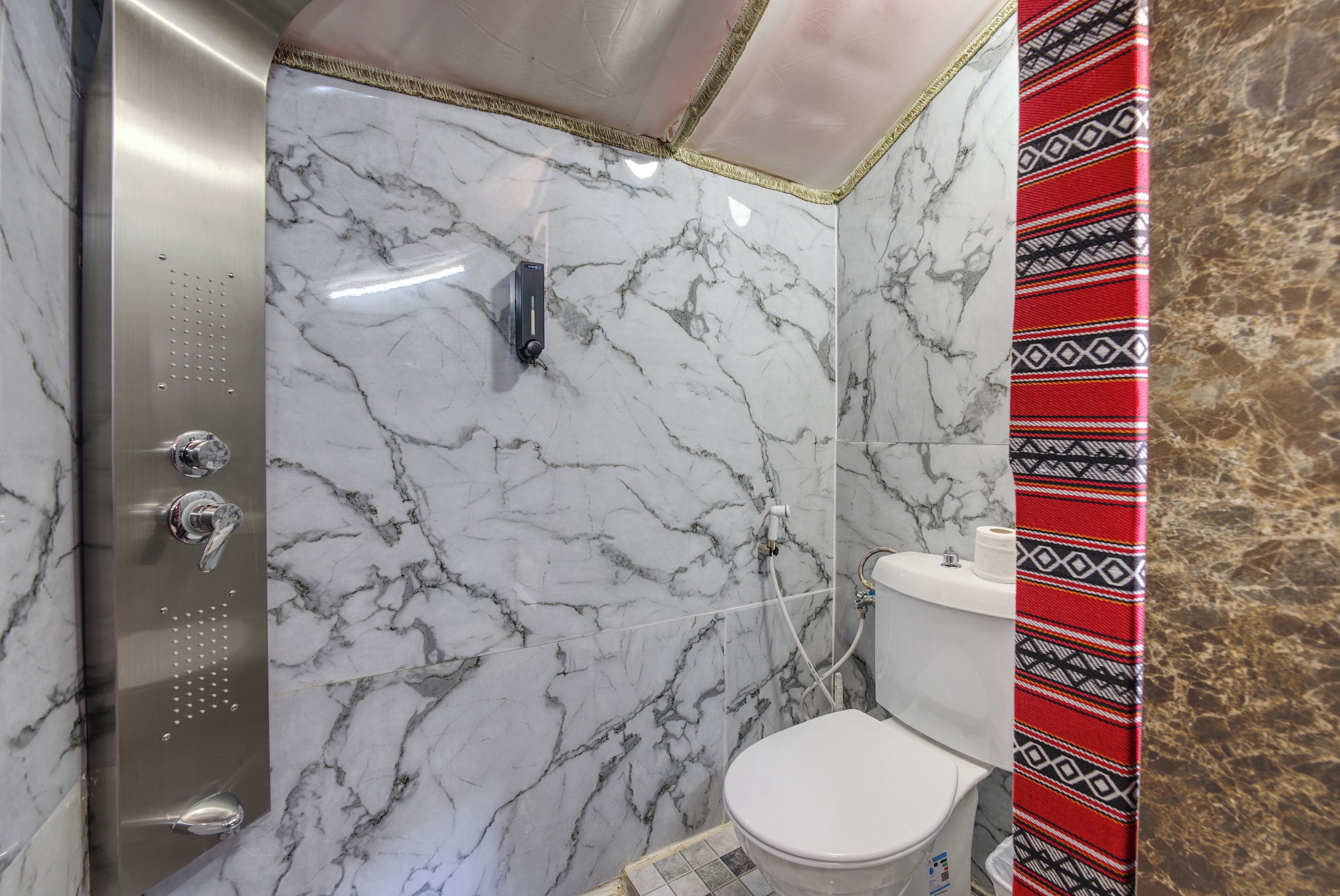 Une salle de bain avec un mur en marbre, une douche et des toilettes.