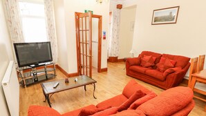 A living room with a sofa set, a television, and a coffee table. - Adeline (Burry Port)