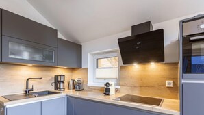 A modern kitchen with grey cabinets, a stainless steel sink, a built-in oven, and a window above the sink.