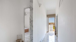 A hallway with a marble column, a chair, and a view of the outside. - 3231 Villino San Basilio by Barbarhouse (Melendugno)