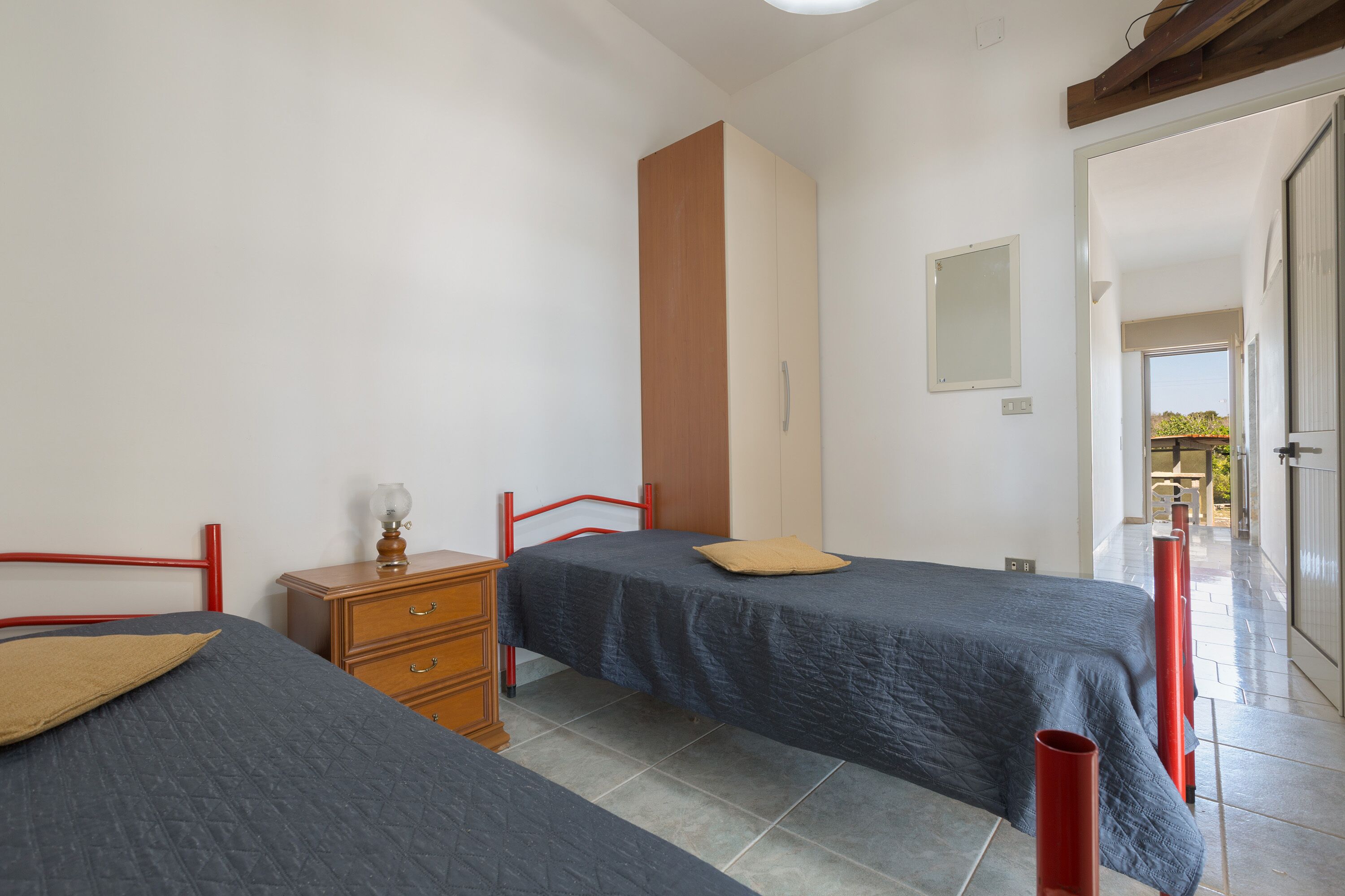 Une chambre avec deux lits, une commode en bois et une chaise rouge.