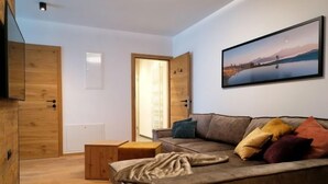Un salon moderne avec un canapé, des coussins, un plancher en bois et une porte donnant sur une autre pièce.