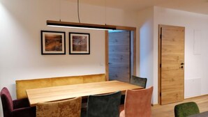 Un espace repas moderne avec une table en bois, des chaises rembourrées et des œuvres d’art encadrées accrochées au mur.