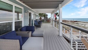 Un espacio al aire libre techado con mobiliario de mimbre y vista a la playa.