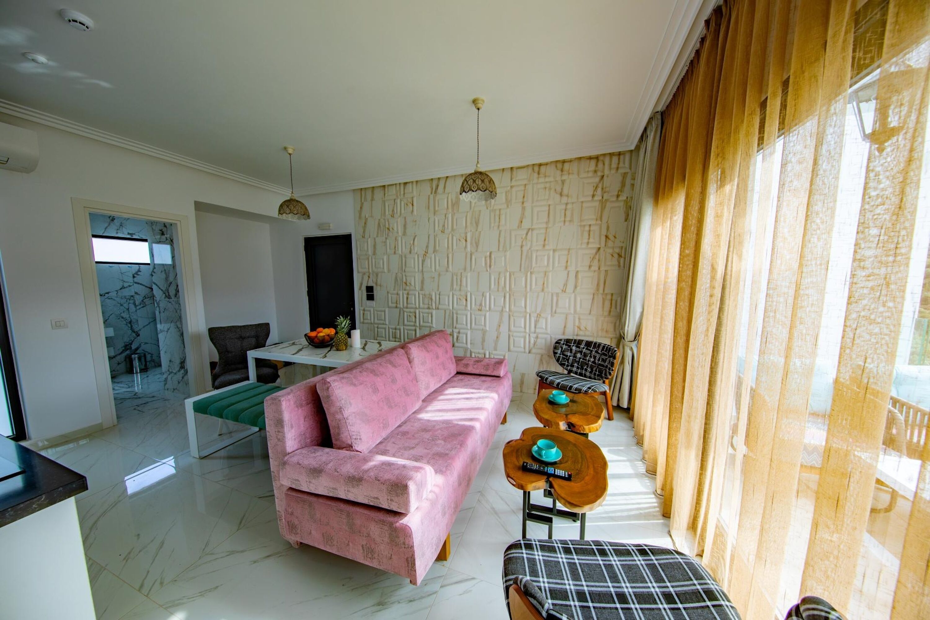 Una sala moderna con un sofá rosa, un comedor con una mesa blanca y una pared con estampado.