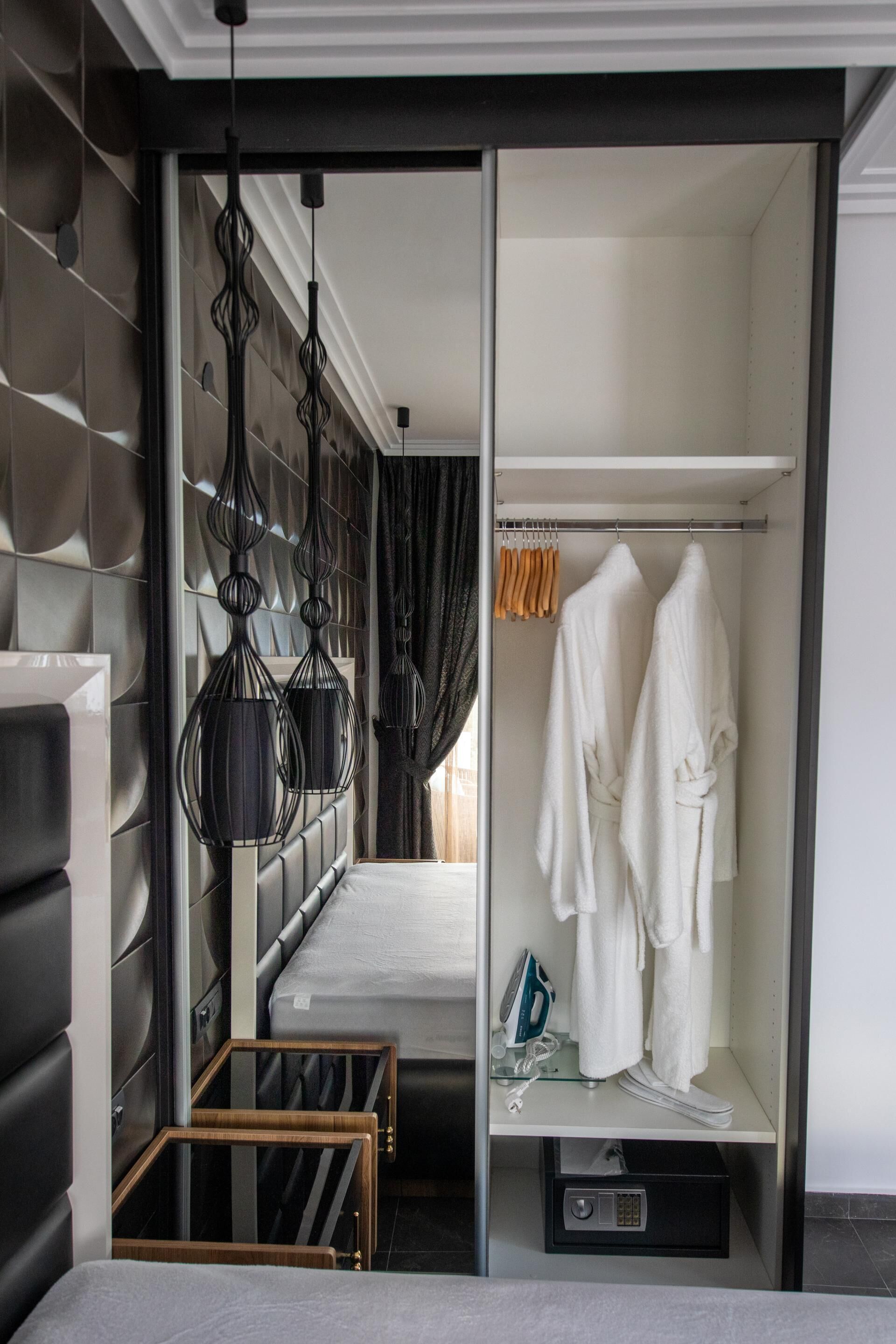 A modern hotel room with a bed, a wardrobe, and a vanity area.