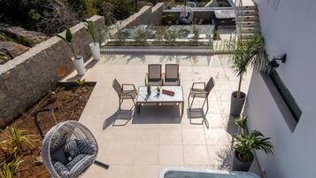 A rooftop terrace with a hot tub, outdoor seating, and a view of the sea and mountains.
