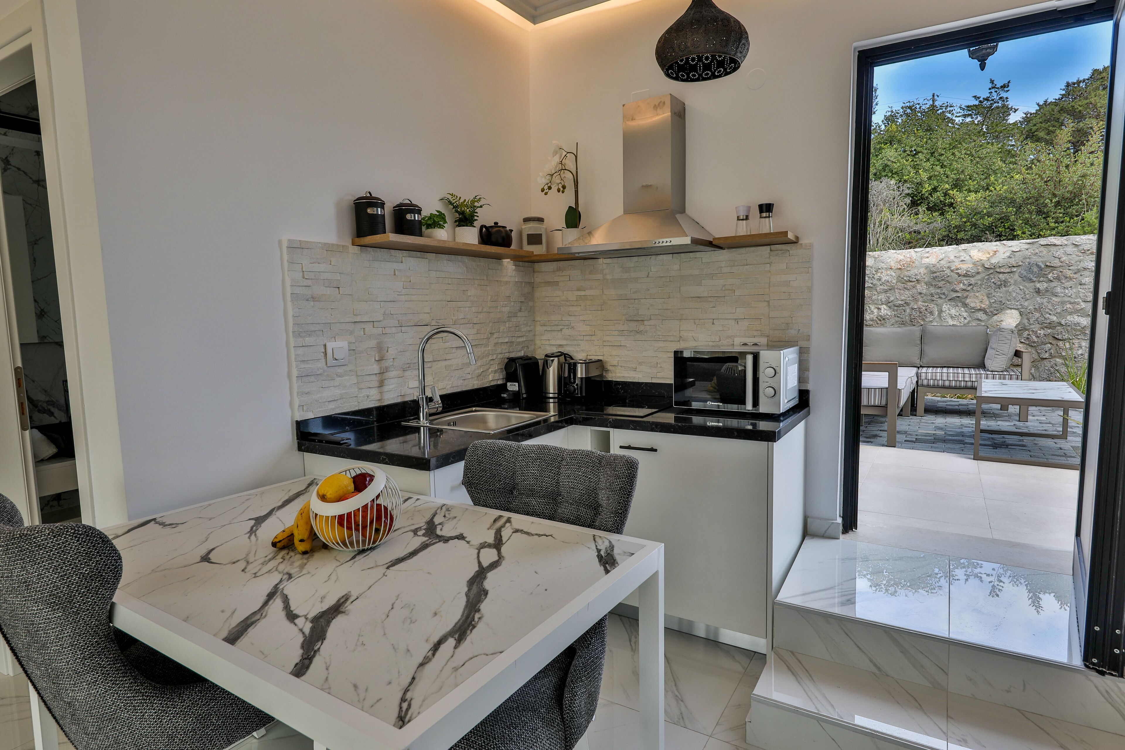 A modern kitchen with a marble countertop, a built-in stove, and a black microwave.