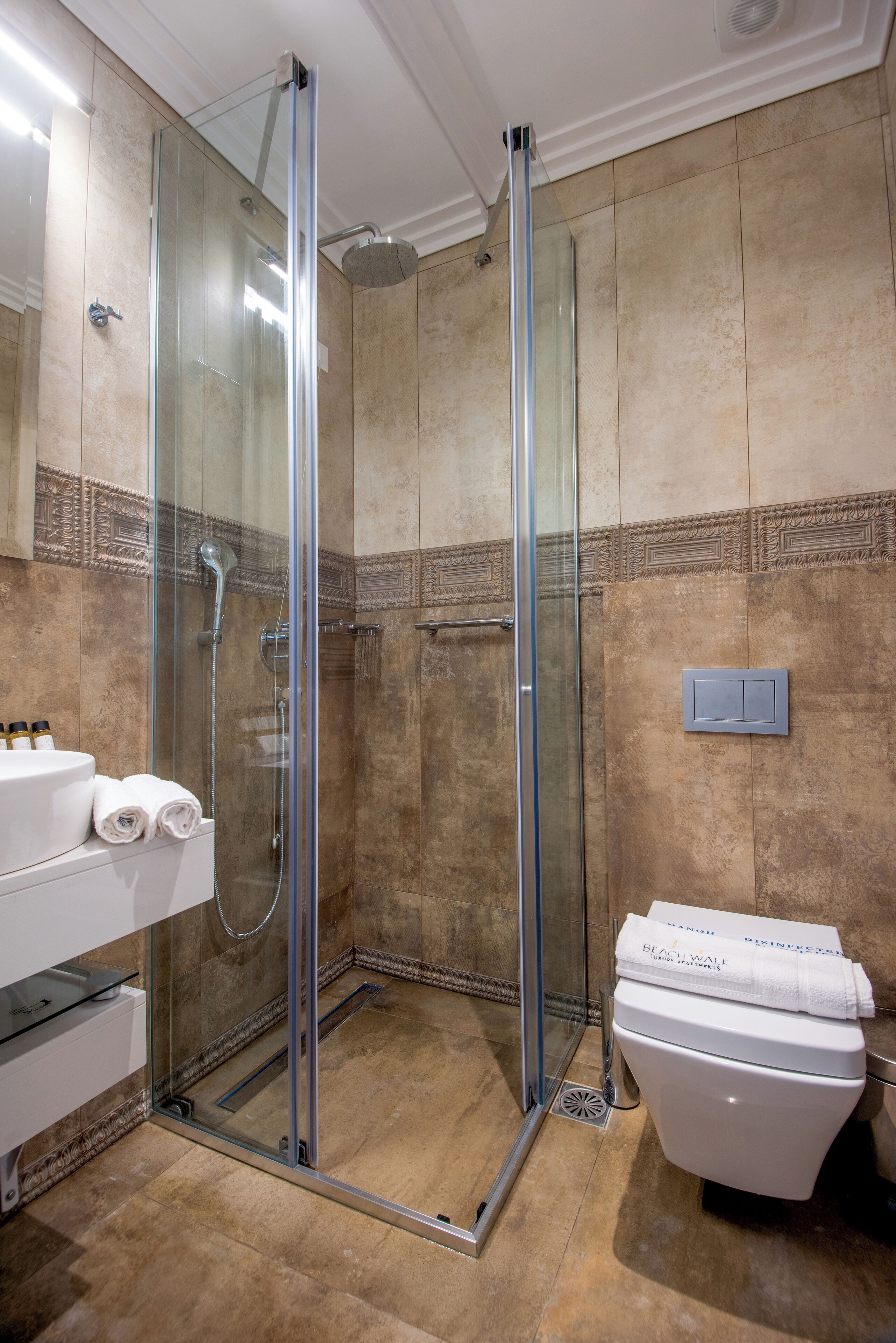 A modern bathroom with a glass-enclosed shower, a white sink, and a toilet.
