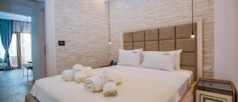 A hotel room with a large bed, a bedside table, a nightstand, and a brick-patterned wall.