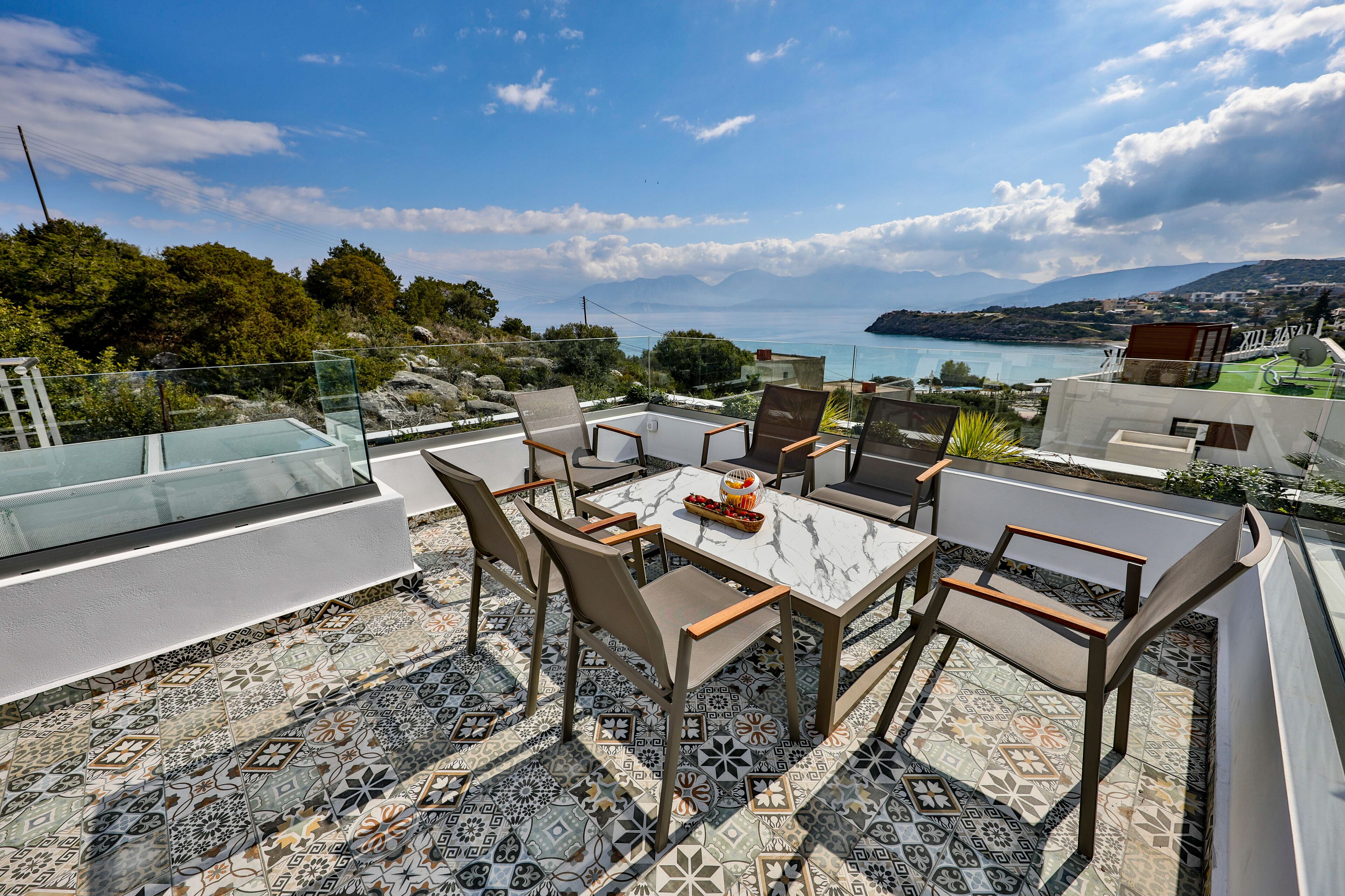 A terrace with a dining set and a view of the sea.