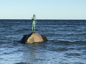 A statue on a rock in the sea.