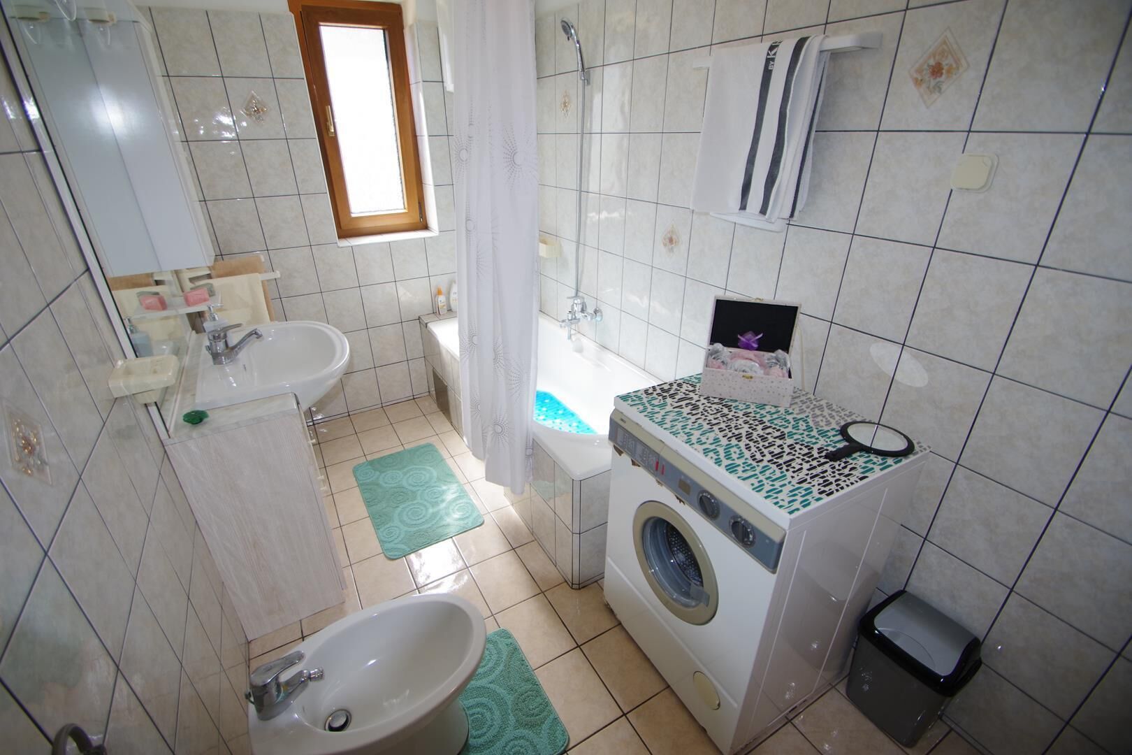 A compact bathroom with a sink, toilet, and washing machine.