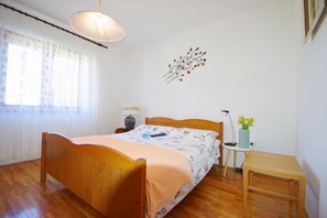 Une chambre à coucher avec un lit en bois, une table de chevet, une lampe, un élément décoratif mural et une fenêtre avec des rideaux.