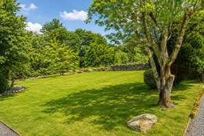 A well-maintained grassy area with a stone wall and trees.