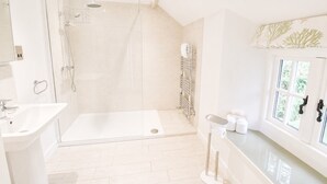 Een moderne badkamer met een douchecabine van glas, een wastafel en een meubel met toiletartikelen.