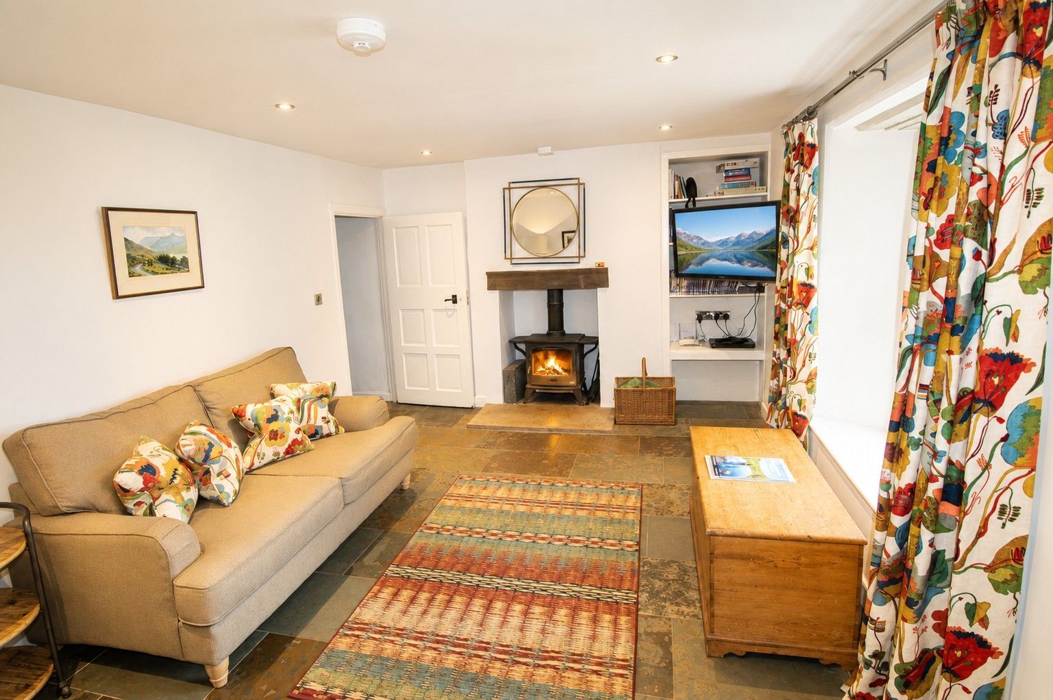 Una sala de estar acogedora con un sofá, una chimenea, un televisor y una cortina estampada.