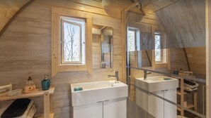 A modern bathroom with two sinks, a large mirror, and a window.