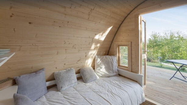 A cozy, wooden interior with a built-in bed and a view of the outdoors.