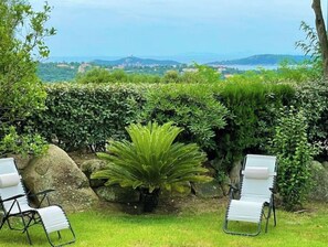 Relax in a serene outdoor space surrounded by lush greenery and a scenic coastal view.