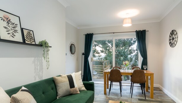A living room with a green sofa, a wooden coffee table, and a dining area with a table and chairs.