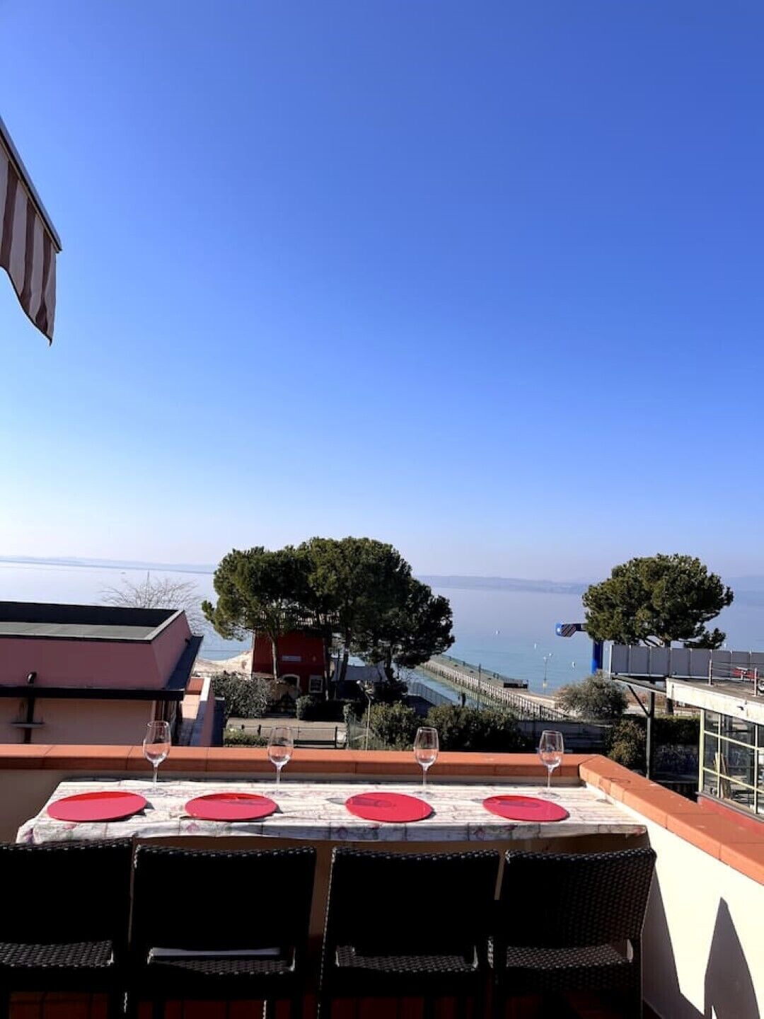 A table set for dining with a view of the sea and trees.