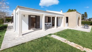Una casa moderna con un portico coperto, un arco in pietra e un prato curato.