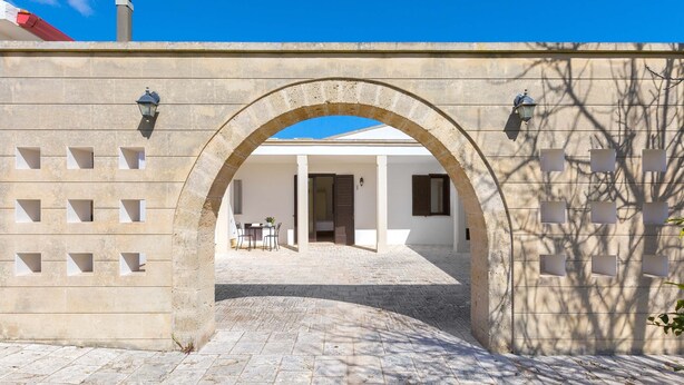 Un arco de piedra que da paso a un edificio con un patio empedrado y una puerta.