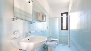 Un baño con un lavamanos grande, inodoro y zona de ducha.